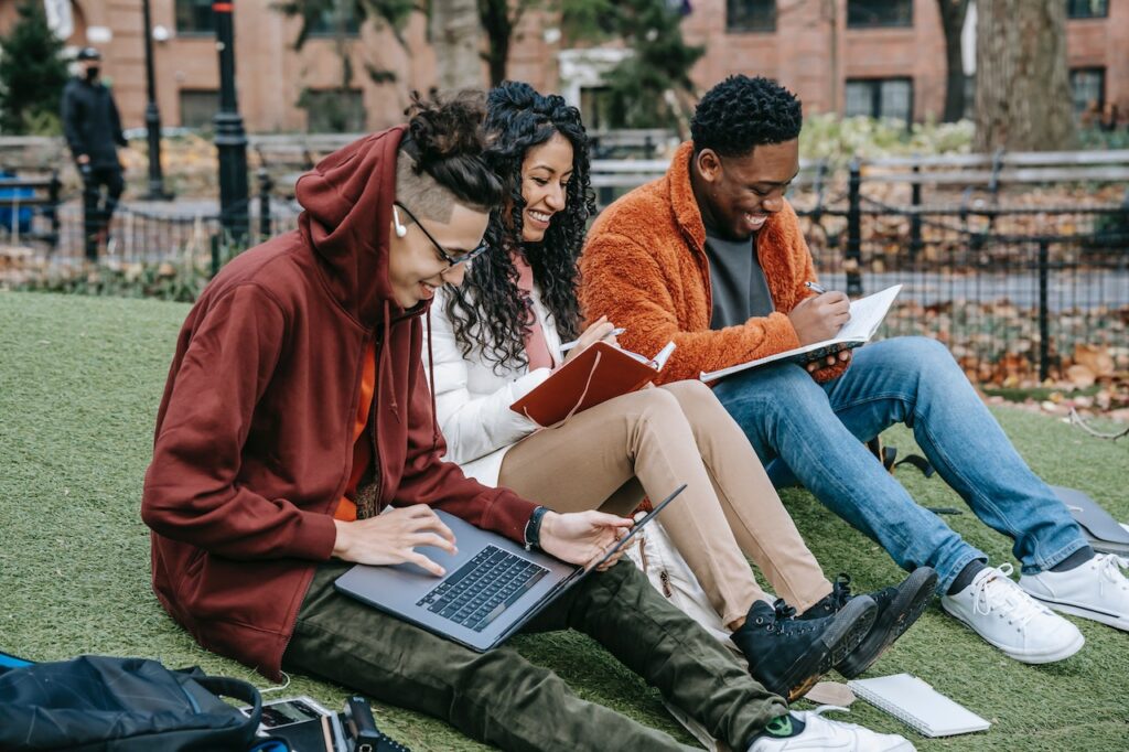 decorative image of three young people working on laptops outdoors
